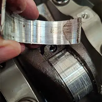 Worn engine bearing showing mechanical damage during engine failure investigation